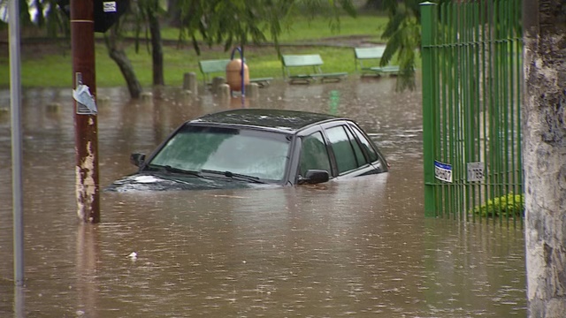 Carro parcialmente submerso em rua alagada de Porto Alegre